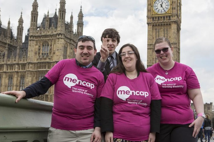 A group of Mencap campaigners in maroon T-shirts pose in front of Big Ben.